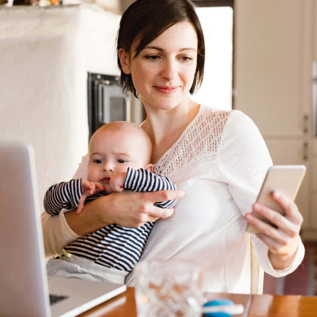 Woman holding baby and viewing the app on phone